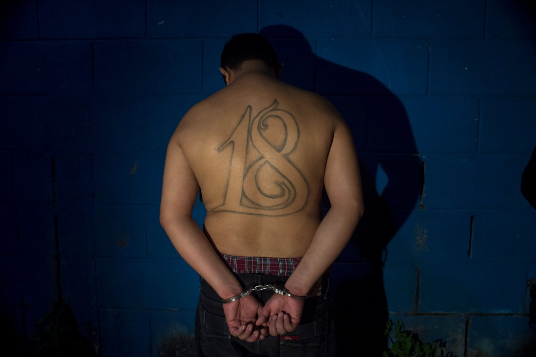 A leader of the Barrio 18 gang stands handcuffed facing a wall after his arrest in San Salvador, El Salvador. (AP)