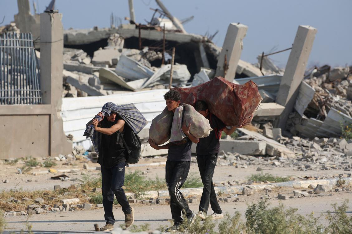 Palestinians walk with bags of humanitarian aid they received at a distribution centre run by the US and Israeli-backed Gaza Humanitarian Foundation. (AFP)