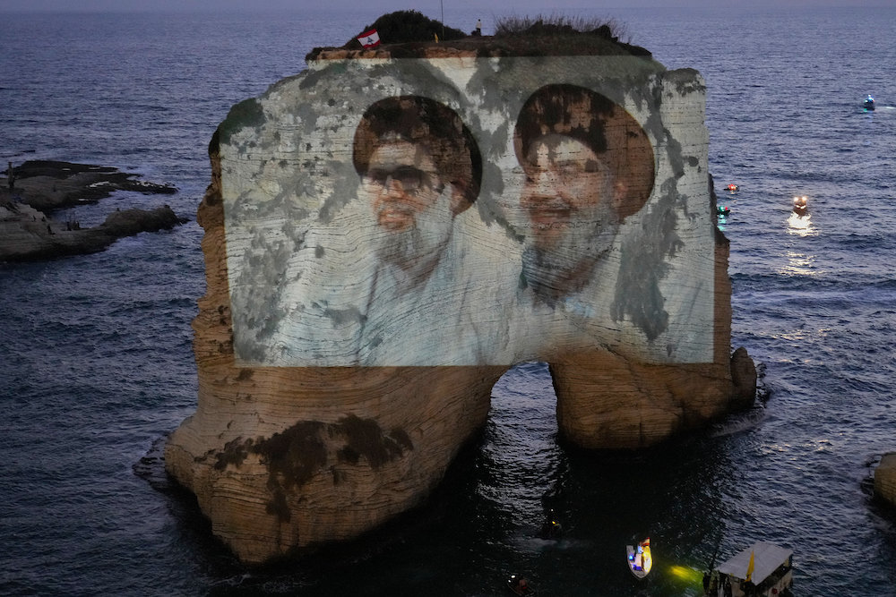 Portraits of former Hezbollah leaders Sayyed Hassan Nasrallah, right, and Hashem Safieddine, are projected onto the landmark Raouche sea rock during an event commemorating the anniversary of their assassination, in Beirut, Lebanon, Thursday, Sept. 25, 2025. (AP)
