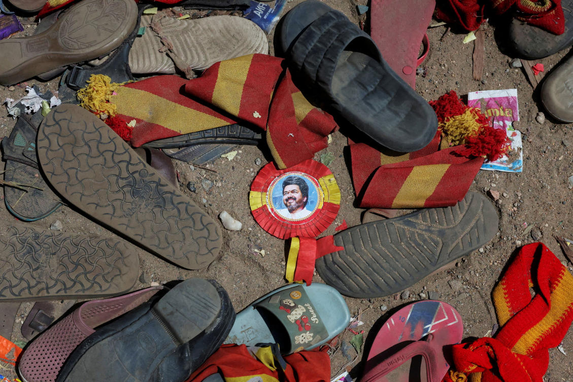 A badge with picture of Vijay, actor and politician, lies amid footwears and other belongings left by attendees at the site of a stampede incident during an election campaign rally held by Tamilaga Vettri Kazhagam party, in Karur district of Tamil Nadu, India, September 28, 2025. Reuters