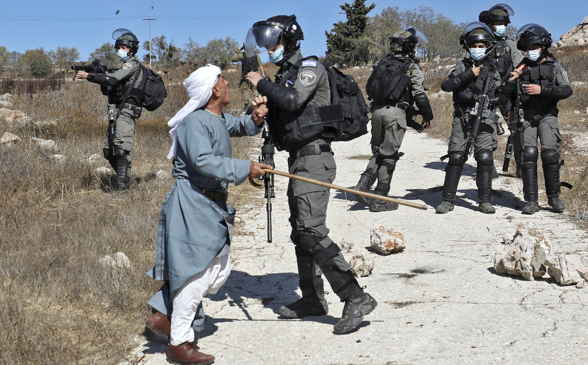 A Palestinian man confronts a member of the Israeli security forces after they intervened in scuffles between Jewish settlers and Palestinian farmers trying to access their lands to harvest olives, in the West Bank village of Burqah, on October 16, 2020. (AFP)