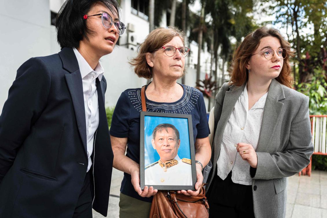 Anne-Marie Lim (C), widow of former Cambodian opposition lawmaker Lim Kimya who was shot dead in Bangkok, holds a picture of her late husband as she speaks to the press before the first witness hearing in the first witness hearing in the trial at the Criminal Court in Bangkok on September 30, 2025. (AFP)