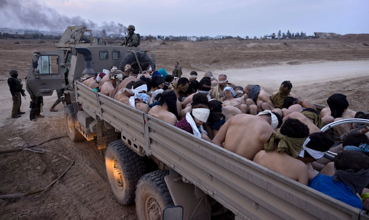 Israeli soldiers stand by a truck packed with bound and blindfolded Palestinian detainees, in Gaza, Dec. 8, 2023. (AP)