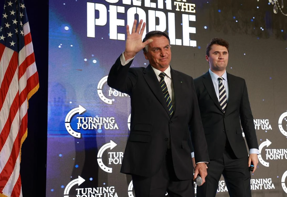 Jair Bolsonaro waves as he stands with Charlie Kirk, co-founder of Turning Point USA, during the Turning Point USA event at the Trump National Doral Miami resort, Doral, Florida, Feb. 03, 2023. (AFP)