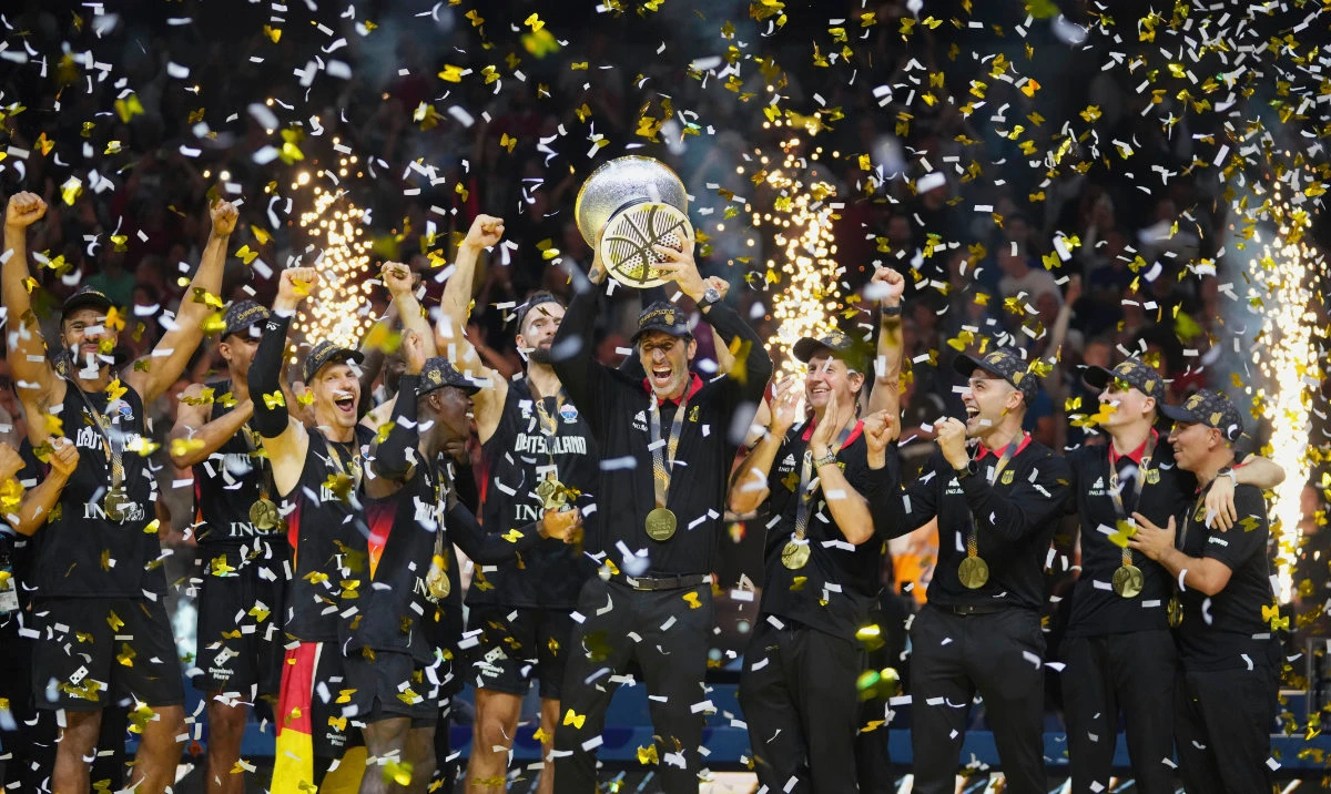 Germany's head coach Alex Mumbru rises the trophy and celebrates with players after winning the Eurobasket, European Basketball Championship final match between Turkey and Germany at the Riga Arena in Riga, Latvia, Sunday, Sept. 14, 2025. (AP)