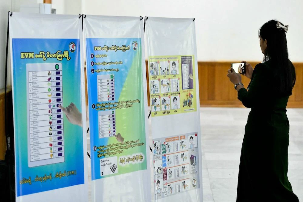 A woman takes a photo of voting guide posters on Sept. 11, 2025 for Myanmar’s long-awaited December election. (AFP)