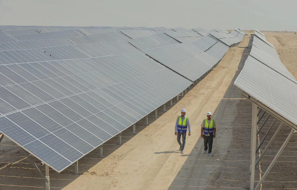 Workers walk between solar panels at a newly opened industrial-scale solar power plant in Karbala, Iraq, Wednesday, Sept. 17, 2025. (AP Photo/Anmar Khalil)