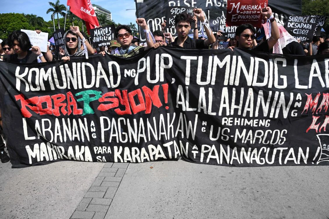 Protesters hold a banner calling for the community to stand up against corruption during a rally against phony flood control projects in Manila on September 21, 2025. (Photo by TED ALJIBE / AFP)