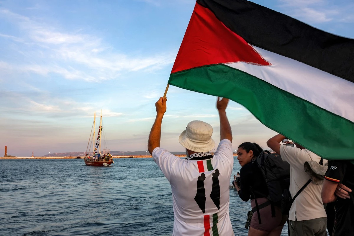 A man waves a Palestinian flag to other activists and human rights defenders riding aboard a vessel departing from Tunisia’s northern port of Bizerte bound for the Gaza Strip, Sept. 14, 2025. (AFP)