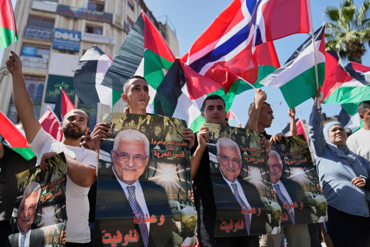 Palestinians carry posters with pictures of President Mahmoud Abbas and read "you kept your promise," during a rally in the West Bank city of Ramallah on Sept. 23, 2025. (AP)