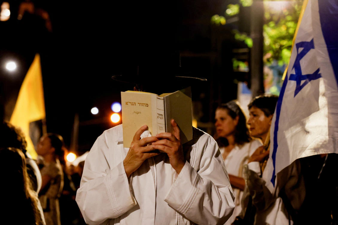 A man holds a Hebrew book as families and supporters of Israeli hostages, kidnapped during the deadly October 7, 2023 attack on Israel by Hamas, gather for a protest as they mark the eve of the Jewish New Year, outside Israeli Prime Minister Benjamin Netanyahu's residence in Jerusalem, September 22, 2025. REUTERS/Ammar Awad