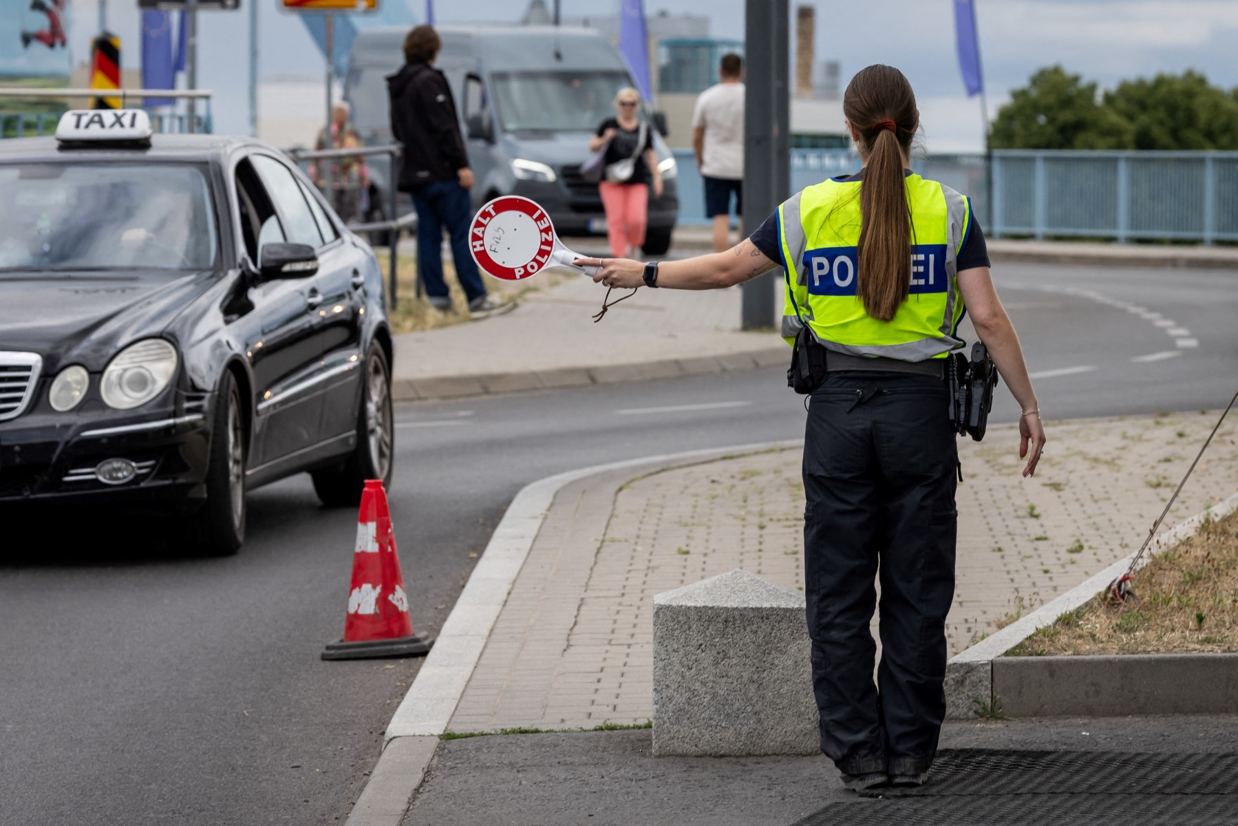 A German police officer holds out the signalling disc during controls at the Polish-German border in Frankfurt an der Oder, Brandenburg, eastern Germany, on July 7, 2025. (AFP)