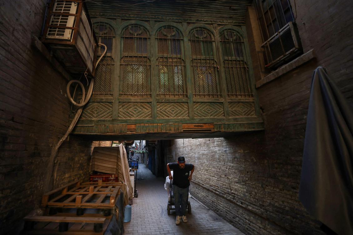 An Iraqi porter pulls a cart through the alleys of Saray Market in central Baghdad, on September 30, 2025. (Photo by AHMAD AL-RUBAYE / AFP)