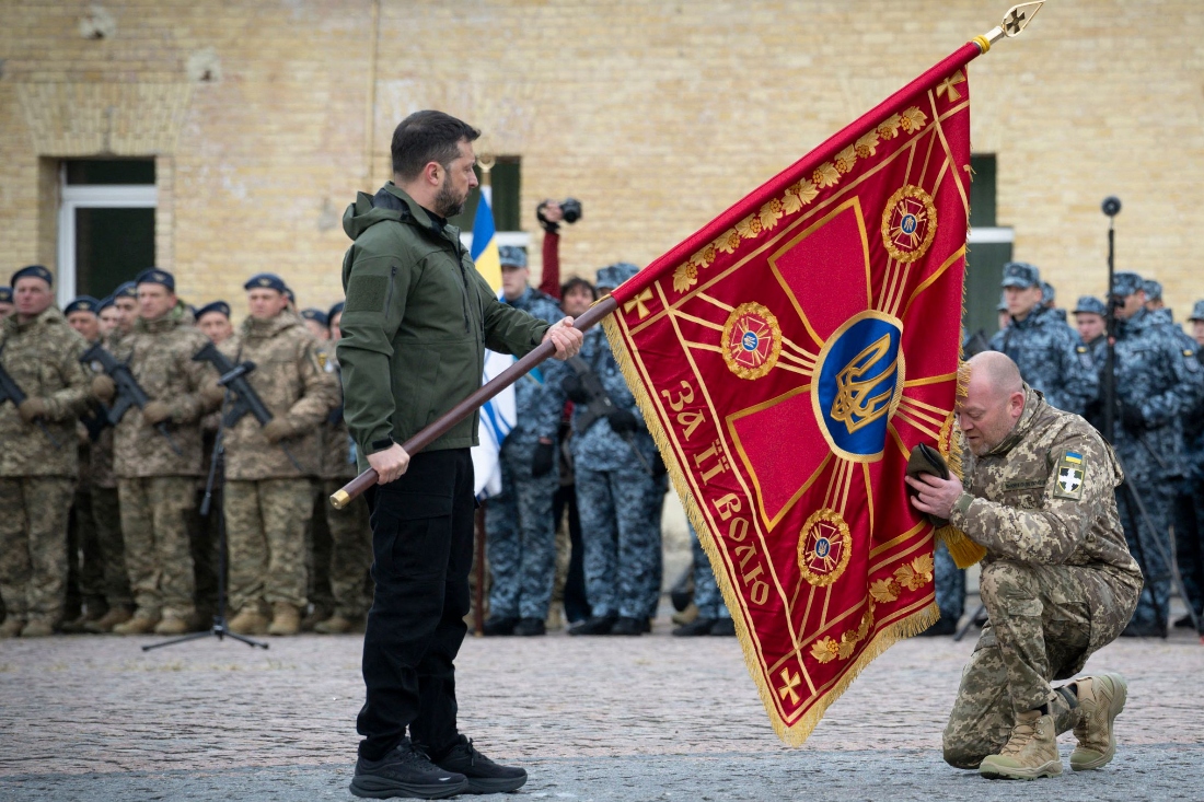 Ukraine's President Volodymyr Zelensky holding a flag insignia as a serviceman pays his respect during a ceremony marking Defenders' Day, a holiday honoring veterans and fallen members of the Ukrainian armed forces, in Kyiv, Ukraine. (Ukrainian Presidential Press Service)