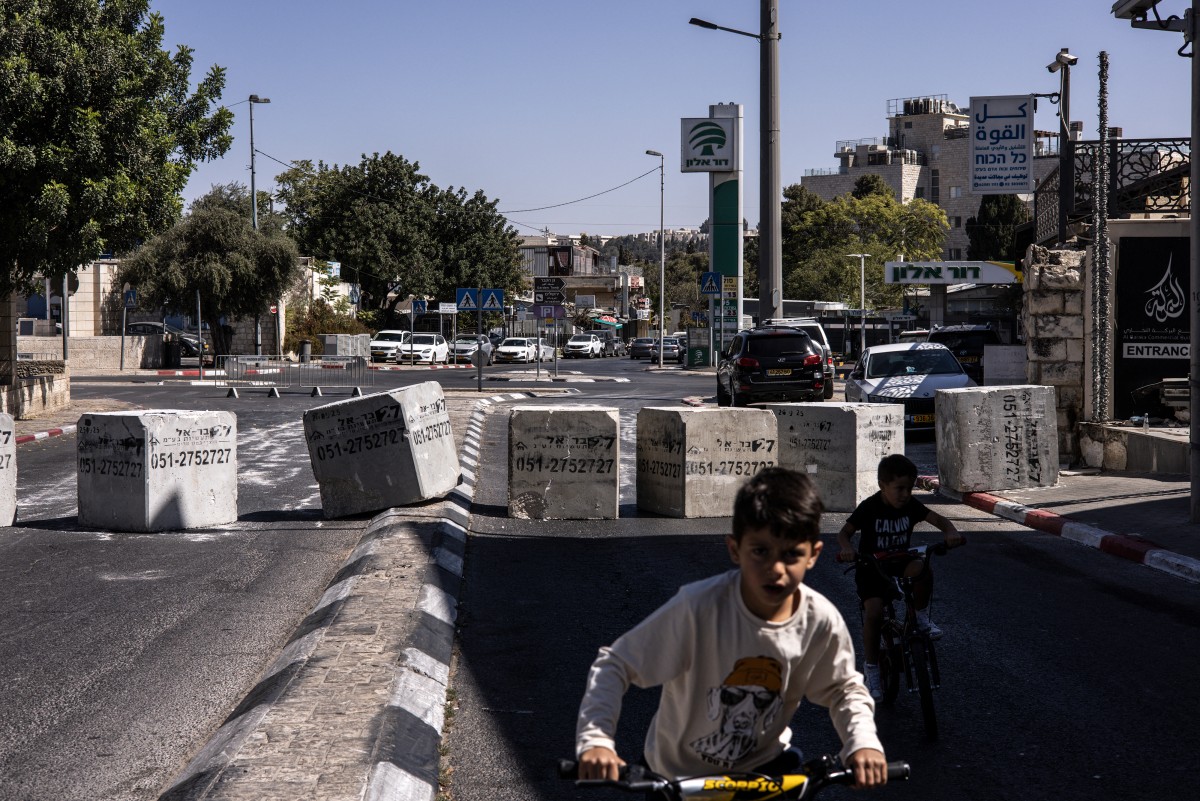 Two Palestinian boys ride bikes in front of a concrete barrier blocking an entrance of the predominantly-Arab east Jerusalem occupied by Israel, during the Jewish holiday of Yom Kippur. Oct. 2, 2025. (AFP)