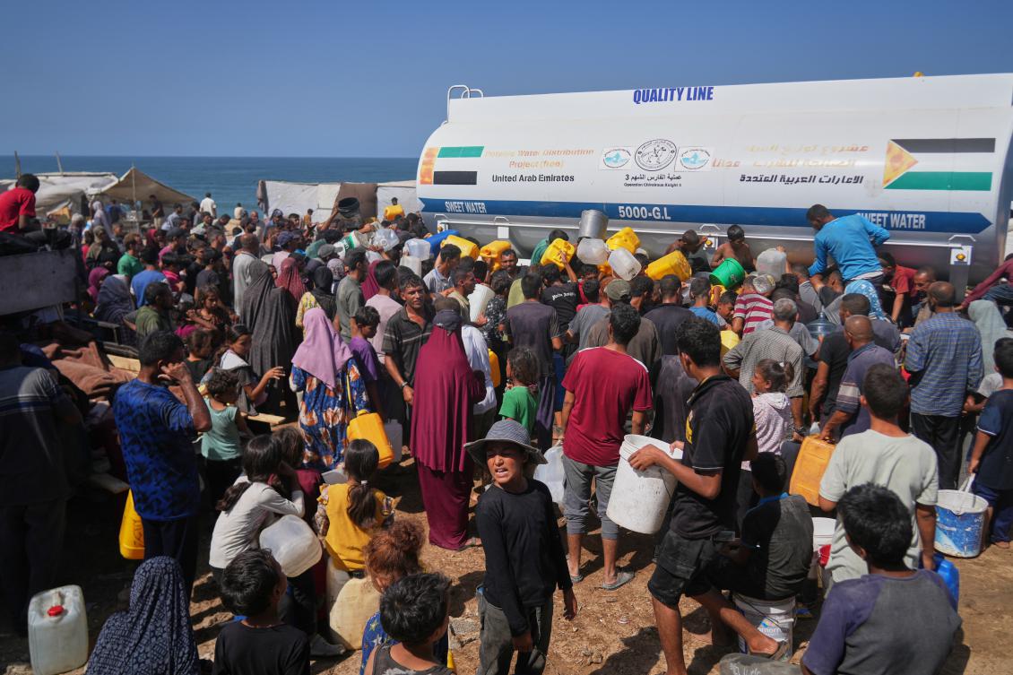 Displaced Palestinians gather to collect water from a truck at a makeshift camp in Nuseirat, central Gaza Strip, Thursday, Oct. 2, 2025.(AP)