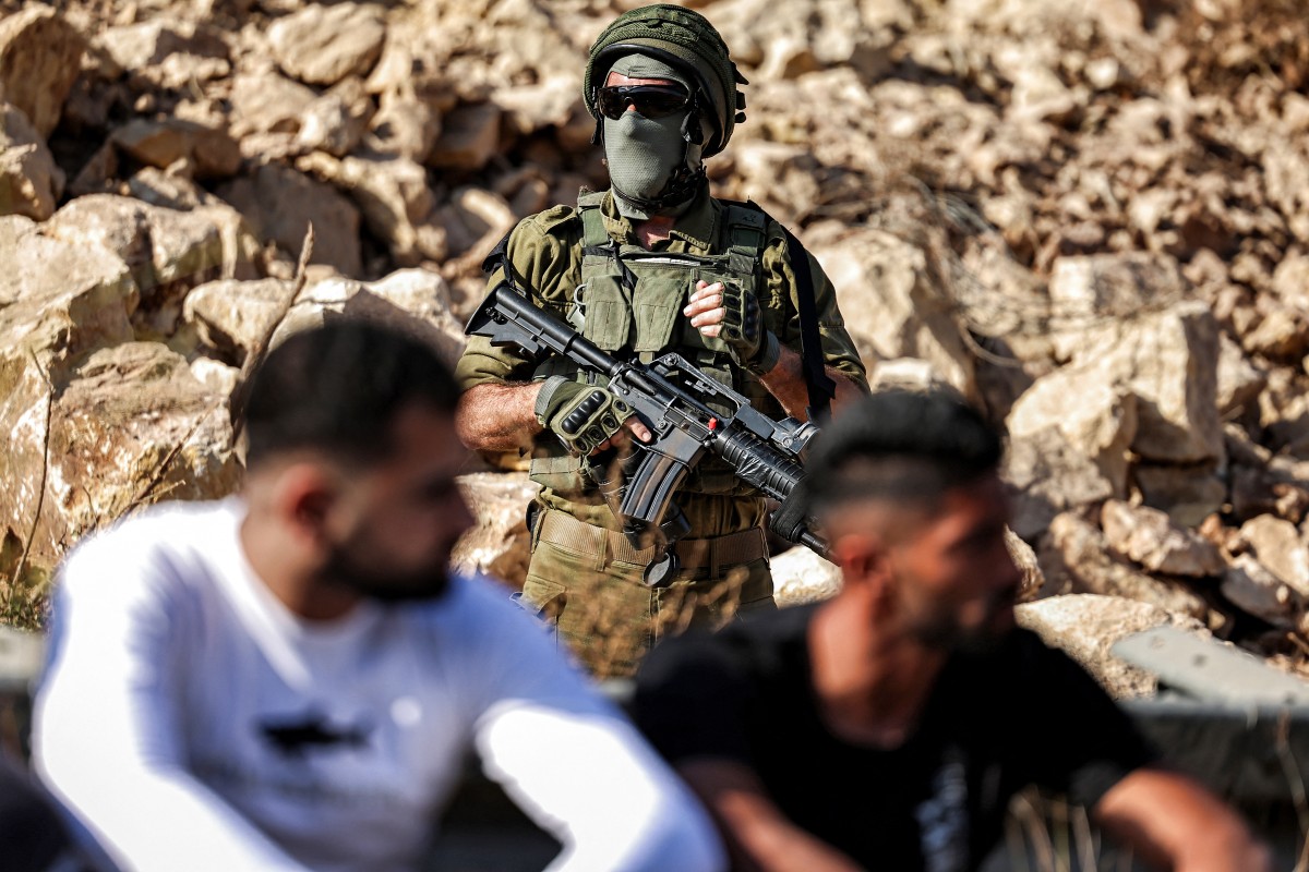 An Israeli army soldier stands guard as Palestinian protesters gather at the site of a new road under construction for the use of Israeli settlers near the Palestinian village of Beit Ur al-Fauqa, west of Ramallah in the occupied West Bank, Sept. 29, 2025. (AFP)
