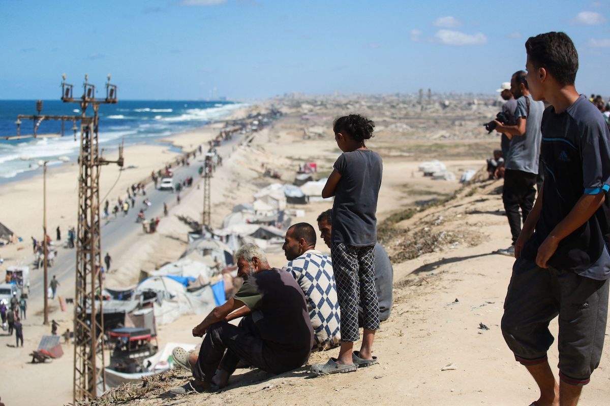 Palestinians watch people arriving with their belongings near Nuseirat refugee camp after fleeing Israel's assault on Gaza City. (AFP)