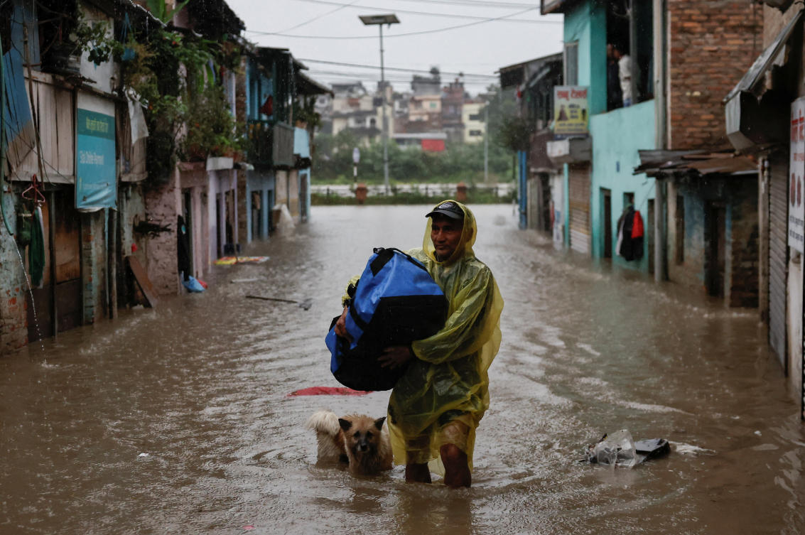 A man carries a bag as he wades through a flooded street along the bank of overflowing Bagmati River following heavy rains in Katmandu, Nepal on Oct. 4, 2025. (Reuters)
