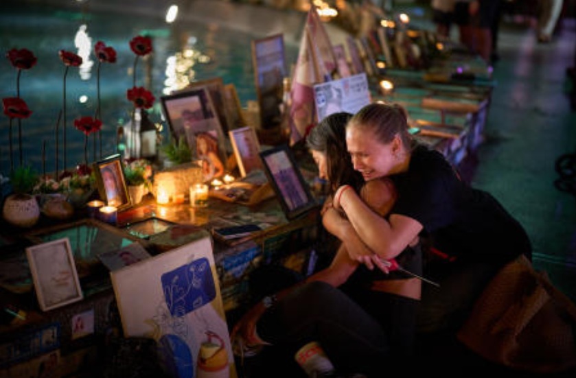 Yuval Miranda and Katya Emelianova cry as they embrace next to the photographs of Israelis who were killed in the deadly Oct. 7, 2023 Hamas attack on Israel, at a memorial marking the 2nd anniversary of the assault, in Tel Aviv, Oct. 7, 2025. (AP)