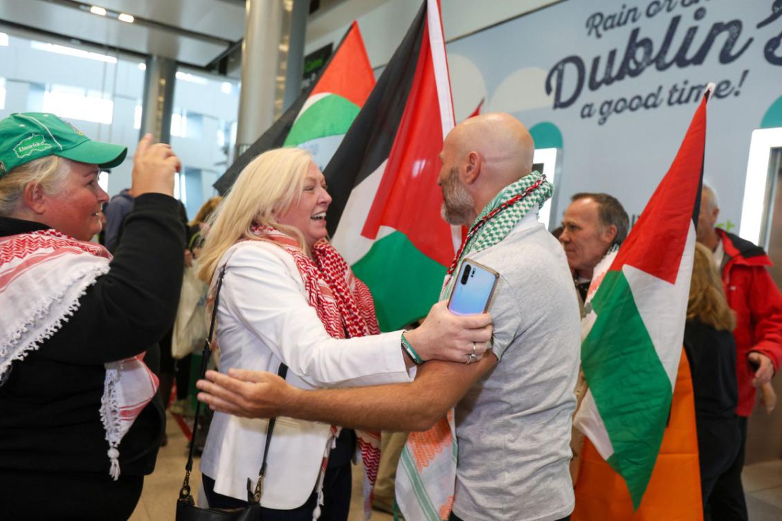 Tadhg Hickey (centre right) one of a group of Irish activists returning, is greeted by supporters as they arrive at Dublin Airport on October 7, 2025, after being deported from Israel. (AFP)