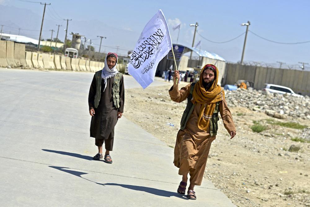 A Taliban fighter carries a Taliban flag in front of the former Bagram military base to celebrate the first anniversary of the withdrawal of US-led troops from Afghanistan on Aug. 31, 2022. (AFP)