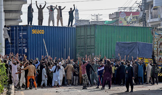 Activists of the Tehreek-e-Labbaik Pakistan (TLP) party shout slogans near their party headquarters, as authorities blocked the road with shipping containers, in Lahore on October 9, 2025, ahead of their pro-Palestinian march towards Islamabad. (AFP)