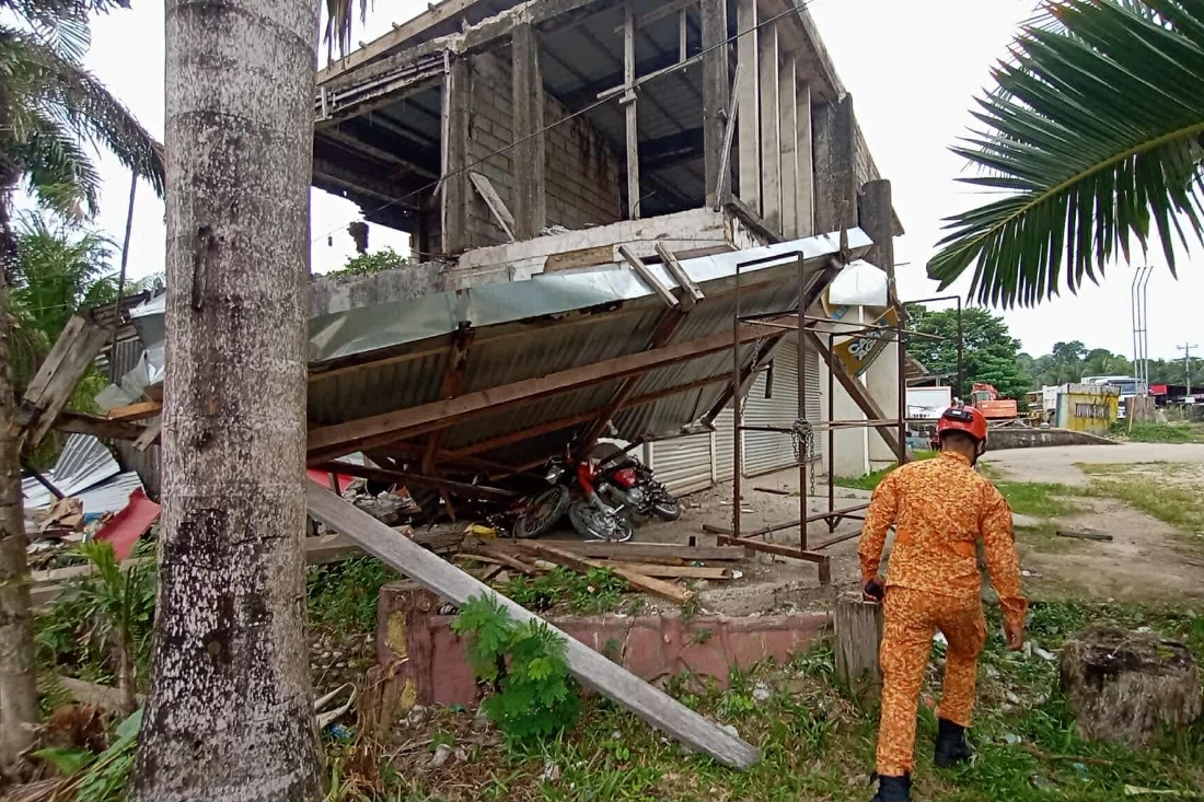In this photo provided by the Bureau of Fire Protection, a firefighter walks past a damaged structure following a strong earthquake in Davao Oriental province, southern Philippines. (AP)