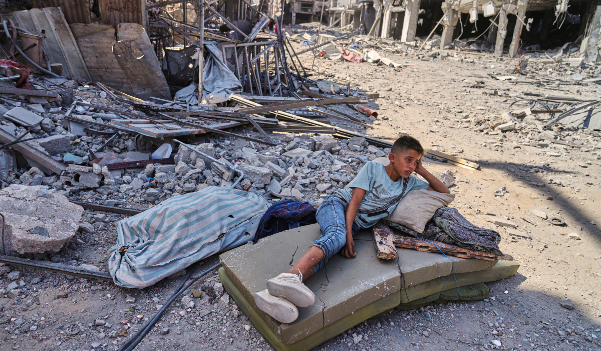 A Palestinian boy lies on a mattress amid the rubble of destroyed buildings in Khan Younis, southern Gaza Strip, Friday, Oct. 10, 2025, after Israel and Hamas agreed to a pause in their war and the release of the remaining hostages. (AP)