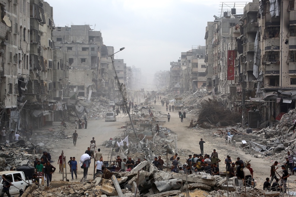 Above, Palestinians make their way past destroyed buildings in Gaza City on Oct. 12, 2025. A UNDP estimated that the two-year Israel-Hamas war had generated at least 55 million tonnes of rubble. (AFP)