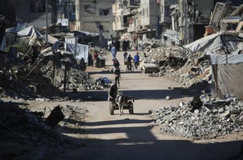 A man rides a donkey cart past destroyed buildings as displaced Palestinians return to their homes in the in Al-Zahra area, north of the Nuseirat refugee camp in the central Gaza Strip, on Oct. 14, 2025, a day after a ceasefire came into effect. (AFP)