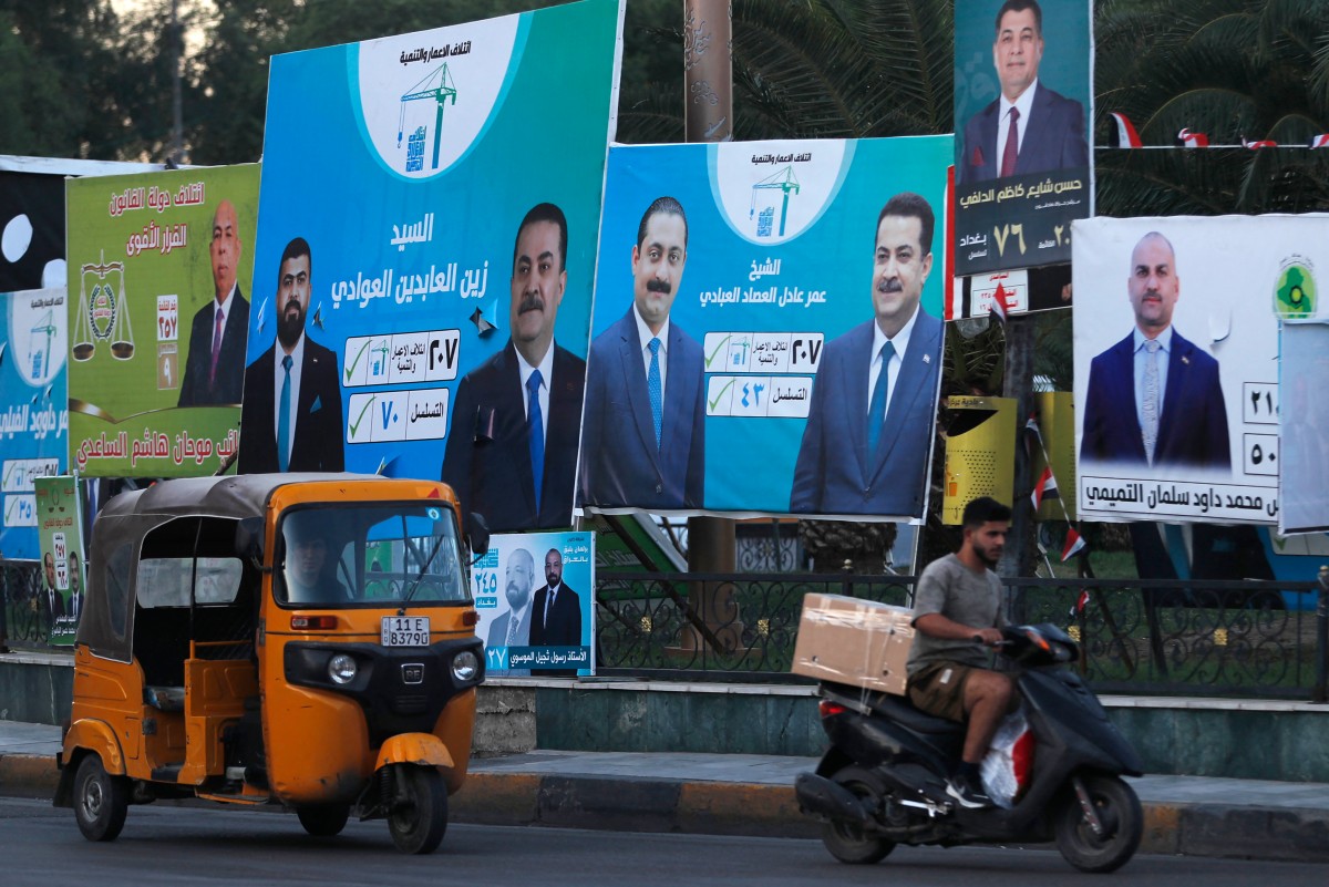 People drive their vehicles past electoral billboards on a street in Baghdad on October 14, 2025, ahead of parliamentary elections on November 11. (File/AFP)