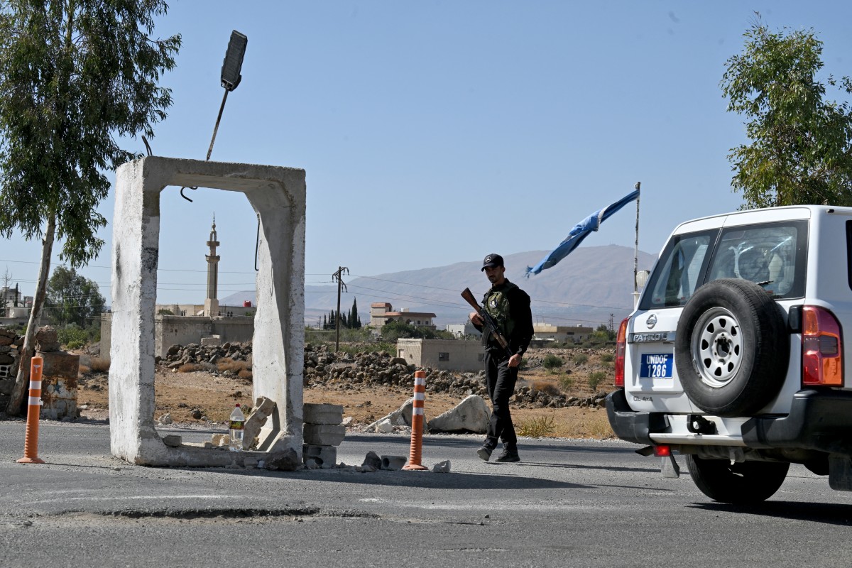 A United Nations Disengagement Observatory Force (UNDOF) vehicle drives past a member of Syria's security forces standing guard outside a former army base near the city of Quneitra in southern Syria, on the edge of the Israeli-annexed Golan Heights on September 21, 2025. (File/AFP)