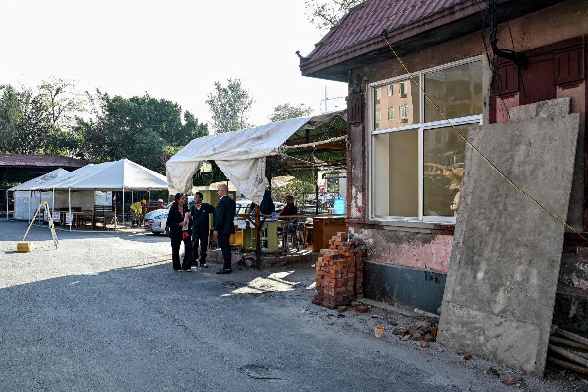 People gather near makeshift tents set up beside an under-renovation structure at the fire-damaged Supreme Court premises in Katmandu on October 15, 2025. (AFP)