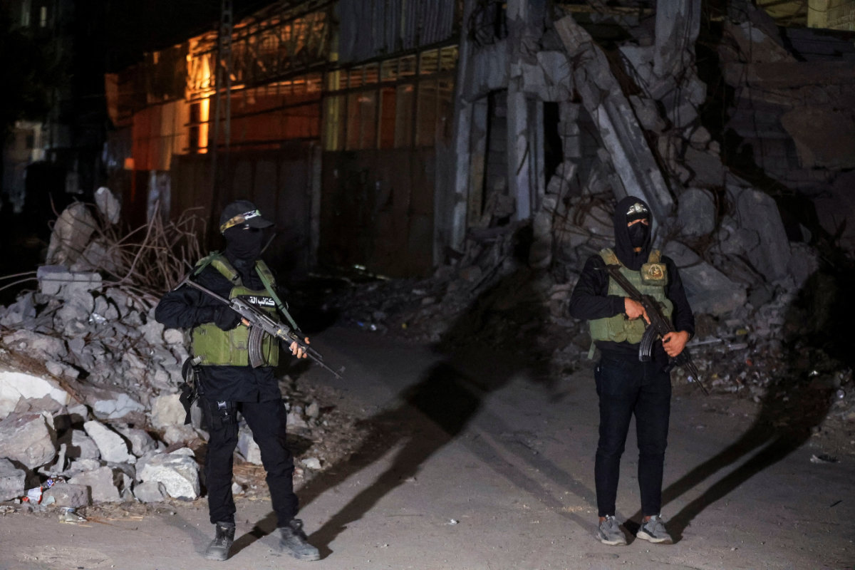Hamas militants stand guard as Red Cross vehicles (not pictured) transport the bodies of hostages who were held in Gaza after they were handed over by Hamas militants as part of a ceasefire and a hostage-prisoner swap deal between Hamas and Israel, in Gaza City, on October 15, 2025. (REUTERS)