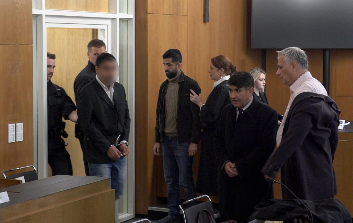 Afghan defendant, 28-year-old Enamullah O. (L), arriving in the courtroom in Aschaffenburg, western Germany, at the start of his trial on October 16, 2025 over a knife attack on toddlers. (AFP)