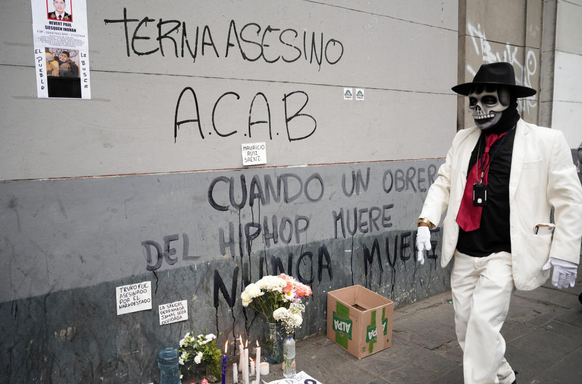 A person wearing a costumed walks next to lit candles that were placed on the street in memory of Mauricio Ruiz, a 32-year-old man who was killed during Wednesday's protest against Peru's President Jose Jeri, days after Jeri took office, in Lima, Peru, October 16, 2025. REUTERS/Angela Ponce