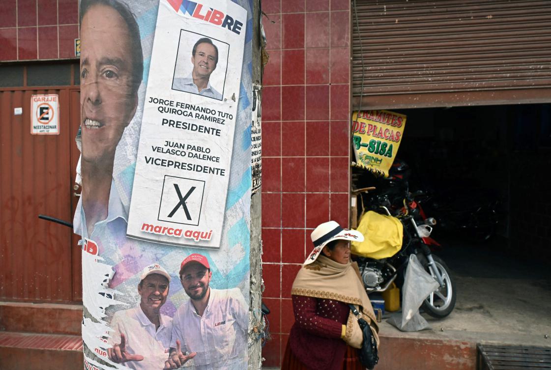 A woman stands next to a poster with the image of a voting ballot for Bolivia’s presidential candidate Jorge Quiroga in El Alto. Bolivia will hold the runoff presidential election on October 19, 2025. (AFP)