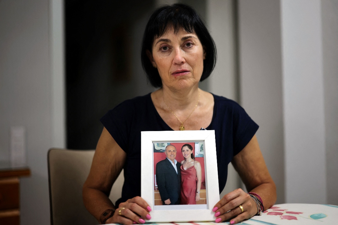 Toni Garcia poses in her apartment with a picture of her husband Miguel and her daughter Sara, 24 years old, who drowned in the basement garage in Benetusser, outskirts of Valencia, Spain. (AFP)