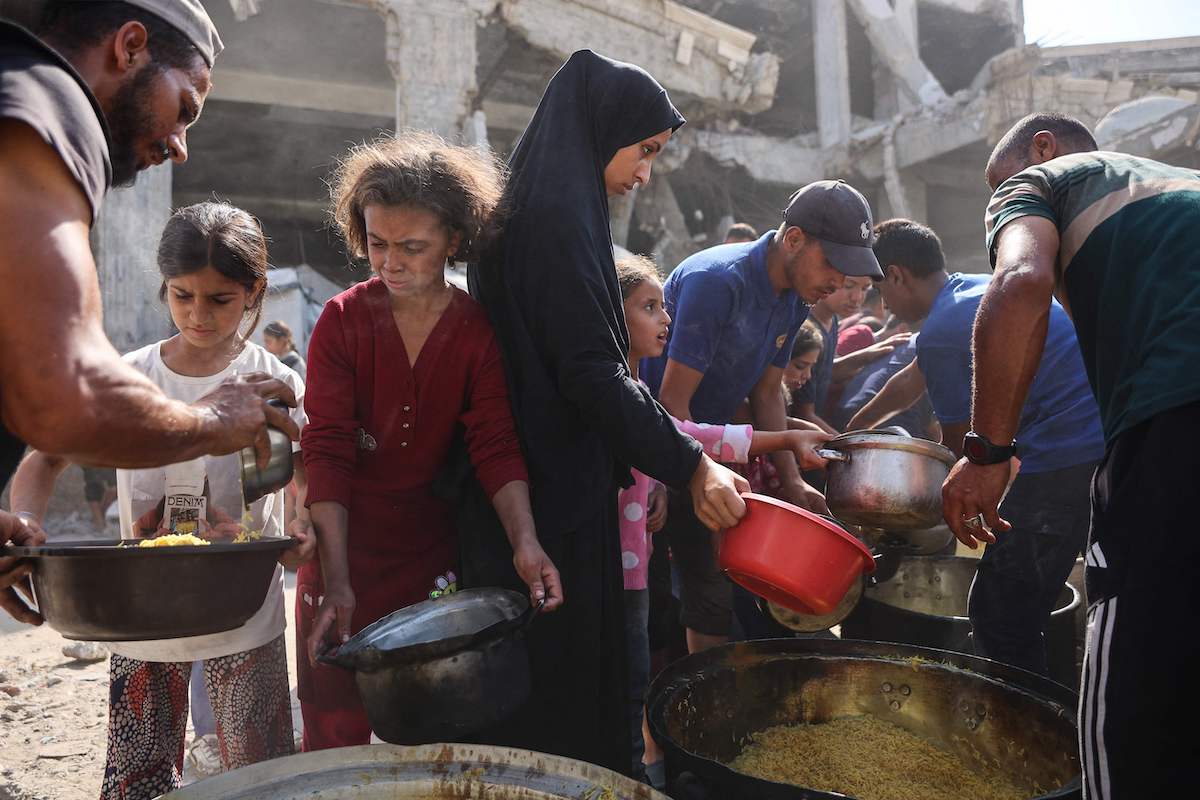 Displaced Palestinians gather to receive food outside the damaged Imam al Shafi’i Mosque in Gaza City on Thursday. (AFP)