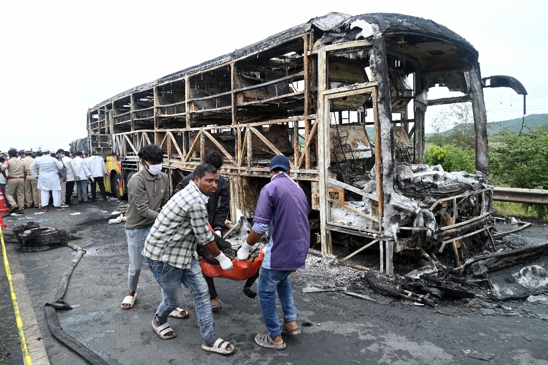 Volunteers remove a dead body from the debris of a passenger bus which caught fire early Friday after a collision with a motorbike on a highway, in Chinnatekuru village, near Kurnool district in Andhra Pradesh state, India. (AP)