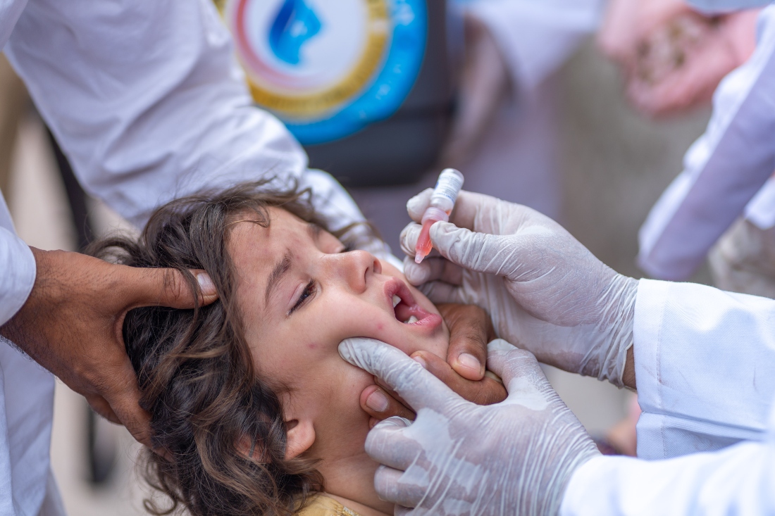 A health worker administers a polio vaccine to a child in Pakistan. (Emirates Polio Campaign)