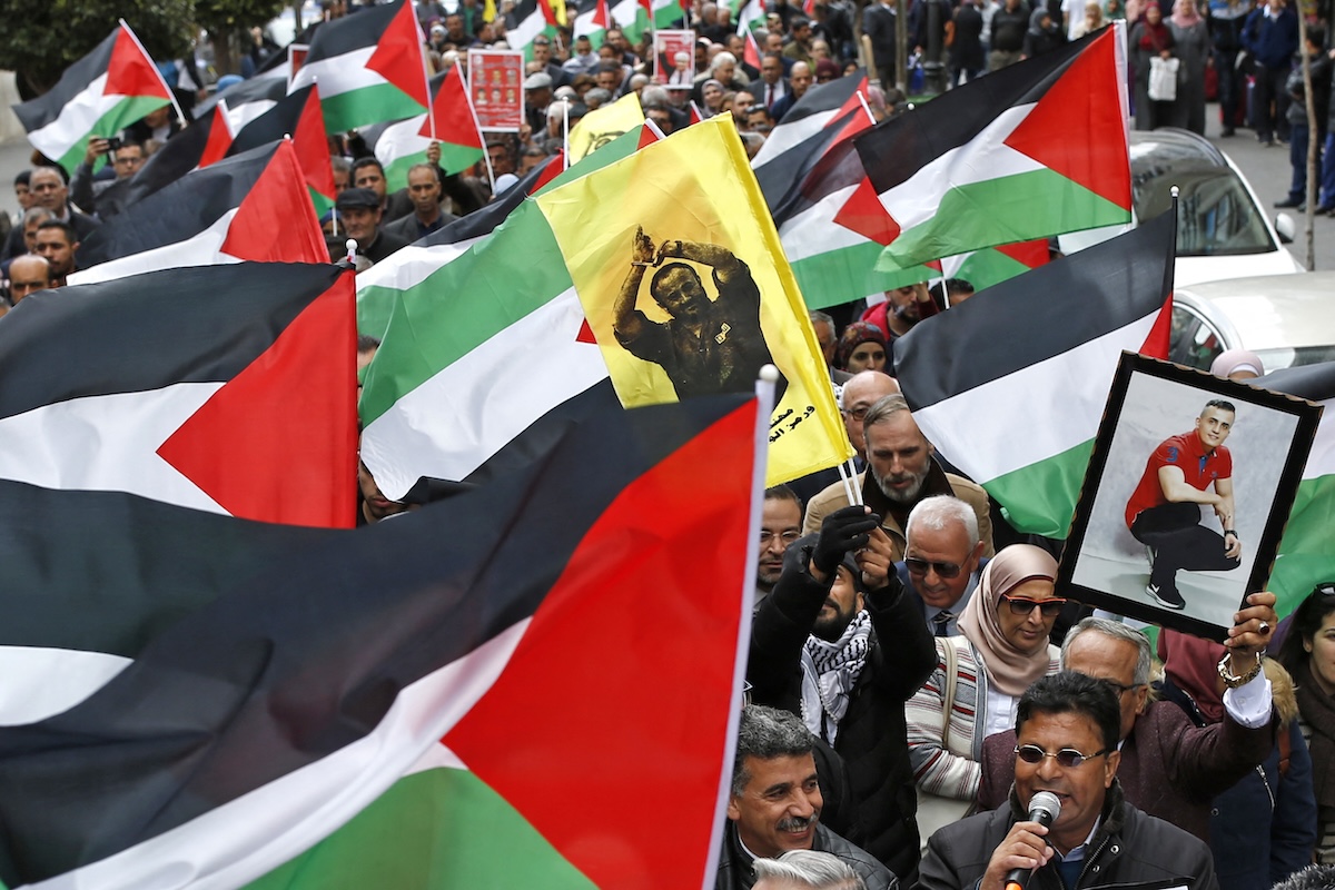Palestinians march with national flags and pictures of prisoners held in Israeli jails, including that of prominent politician Marwan Barghouthi (C, yellow), during a rally marking Palestinian Prisoners' Day in the West Bank city of Ramallah on April 17, 2019. (FILE/AFP)