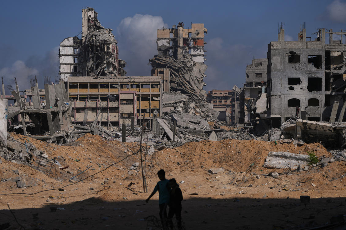 Palestinians walk through the destruction caused by the Israeli air and ground offensive in the Al-Shati camp, Gaza City, on Friday. (AP)