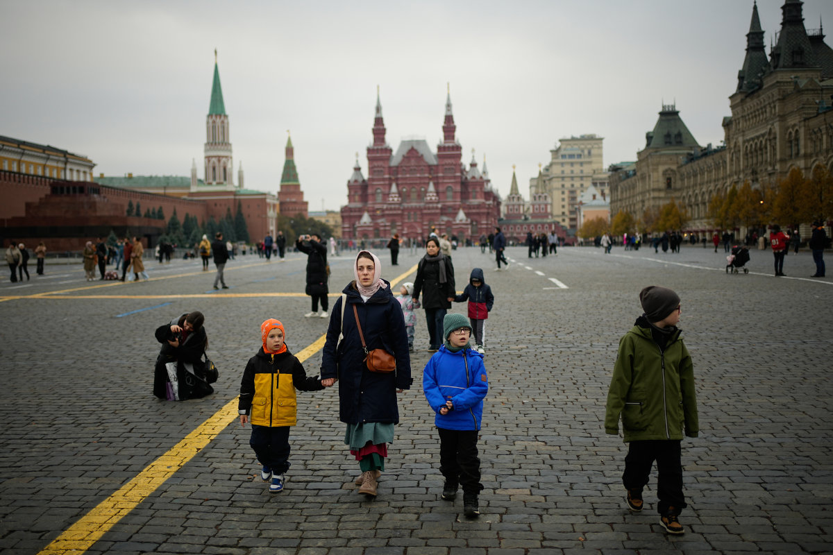 A woman holds a boy as she walks through Red Square on Oct. 20, 2025, with the Historical Museum in the background. (AP Photo/File)