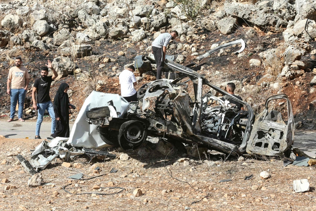 People inspect the wreckage of a vehicle targeted by an Israeli strike in the southern Lebanese village of Haruf. (AFP)