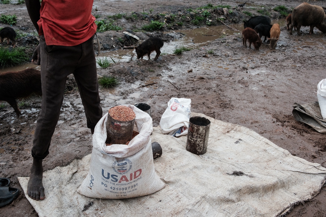 A man sells sorghum on the street from an old USAID bag and tin in Maban, South Sudan. (AFP)