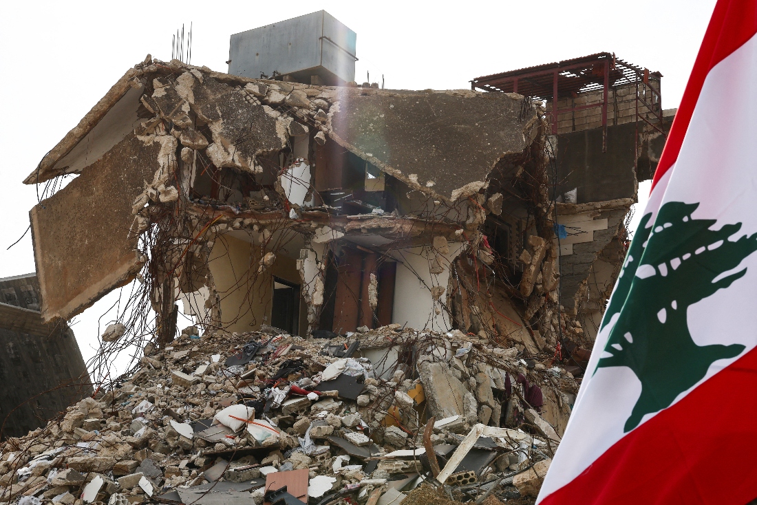 A view shows Lebanon's flag next to a damaged building in the southern Lebanese village of Kfar Kila, in Lebanon. (Reuters)