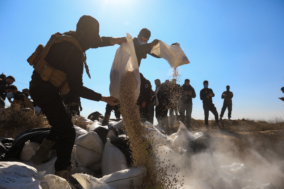 Members of the security forces of Syria's new authorities empty sacks of Captagon into a ditch to burn them in a field near the Fourth Division's Security Bureau on the outskirts of Damascus. (AFP)