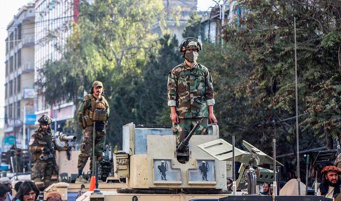 Taliban security personnel stand over military vehicles as Afghan men gather in their support during a rally in Khost on October 13, 2025, amid heavy cross-border clashes between Afghanistan and Pakistan. (AFP)
